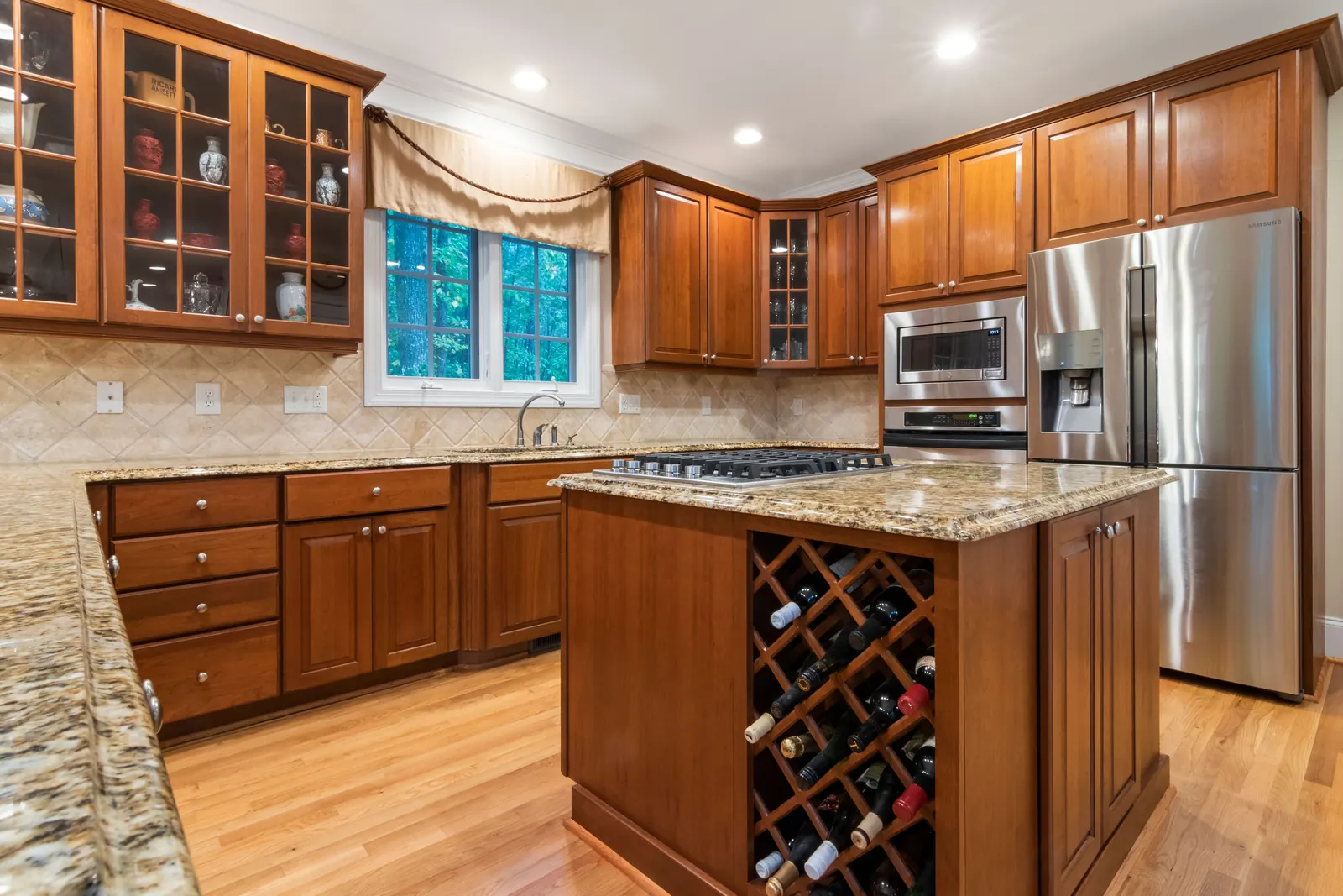 Cherry cabinets with glass upper doors and an island wine rack