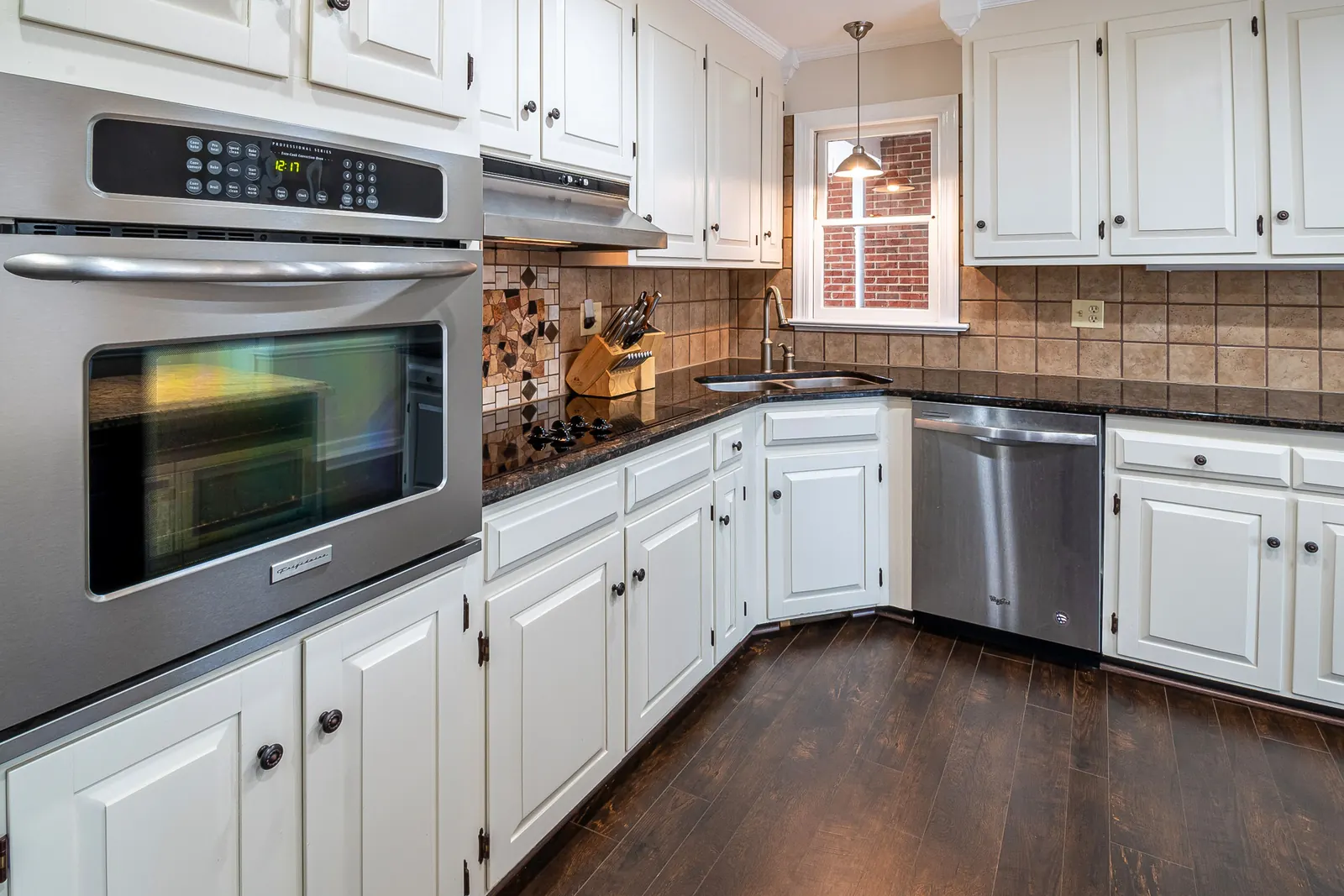 White raised-panel kitchen cabinets with a stainless double wall oven